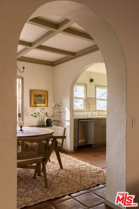 dining area with coffered ceiling, sink, and beam ceiling