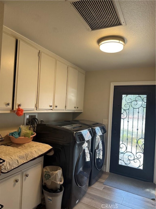 washroom with cabinets, light wood-type flooring, and washing machine and clothes dryer