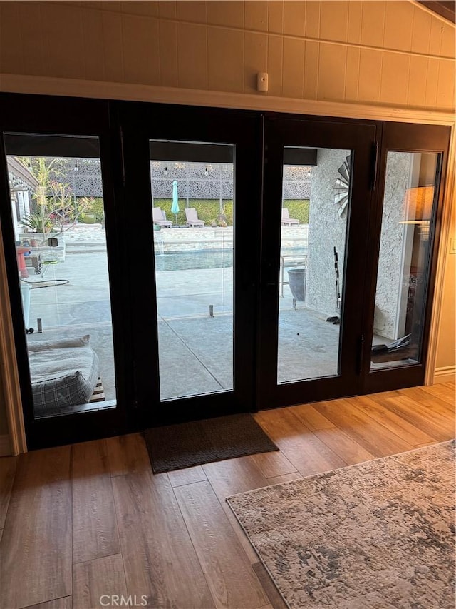 doorway to outside featuring hardwood / wood-style flooring, wood walls, and french doors