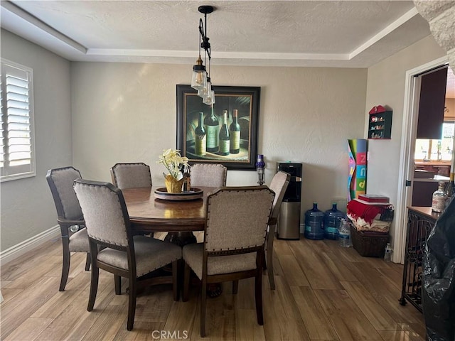 dining room featuring hardwood / wood-style flooring, a raised ceiling, and a textured ceiling