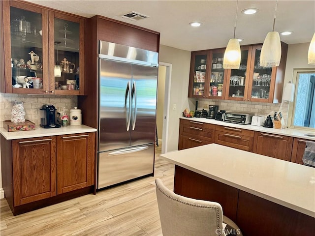 kitchen with stainless steel built in fridge, decorative backsplash, light hardwood / wood-style floors, and hanging light fixtures