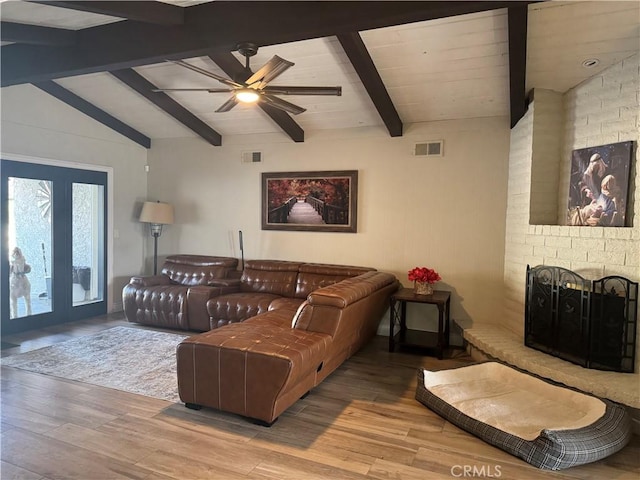 living room featuring ceiling fan, light hardwood / wood-style flooring, a brick fireplace, and lofted ceiling with beams