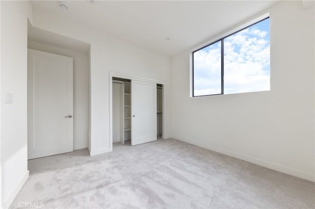 unfurnished bedroom with light colored carpet and a closet