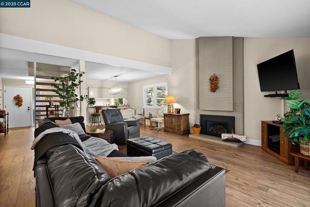 living room featuring a large fireplace, light hardwood / wood-style flooring, and a notable chandelier