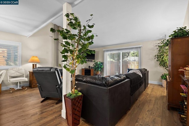 living room with hardwood / wood-style flooring, ornamental molding, and vaulted ceiling