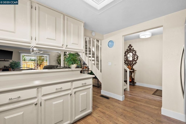 kitchen with white cabinets, light wood-type flooring, and a skylight