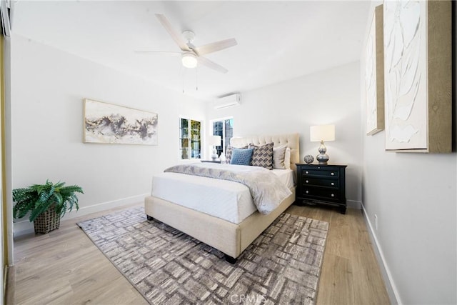 bedroom featuring hardwood / wood-style flooring, a wall unit AC, and ceiling fan