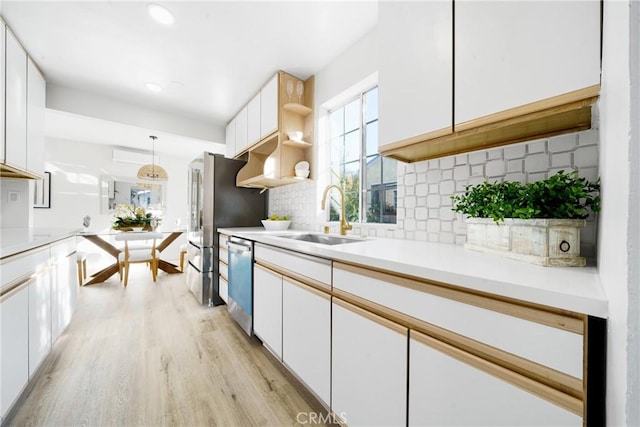 kitchen with tasteful backsplash, stainless steel appliances, sink, pendant lighting, and white cabinets