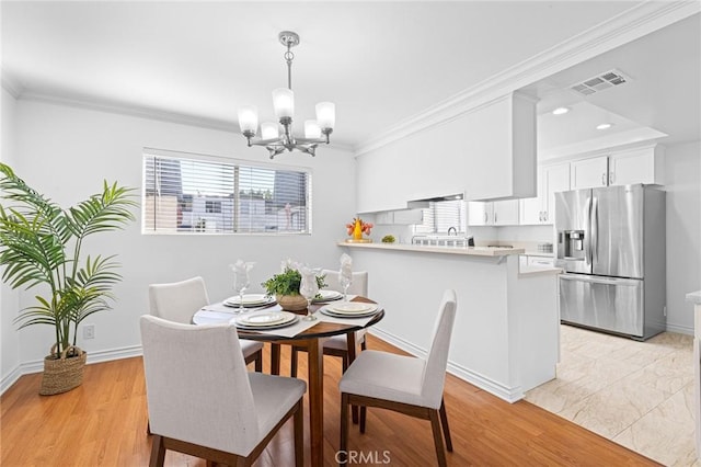 dining space featuring a notable chandelier, crown molding, and light hardwood / wood-style flooring