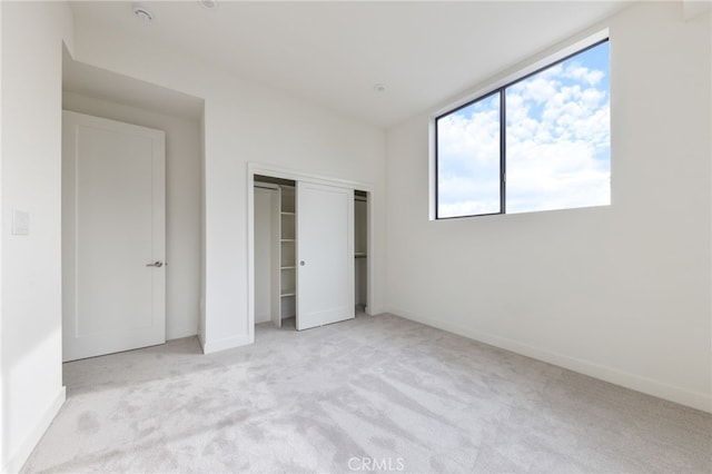 unfurnished bedroom featuring light carpet and a closet