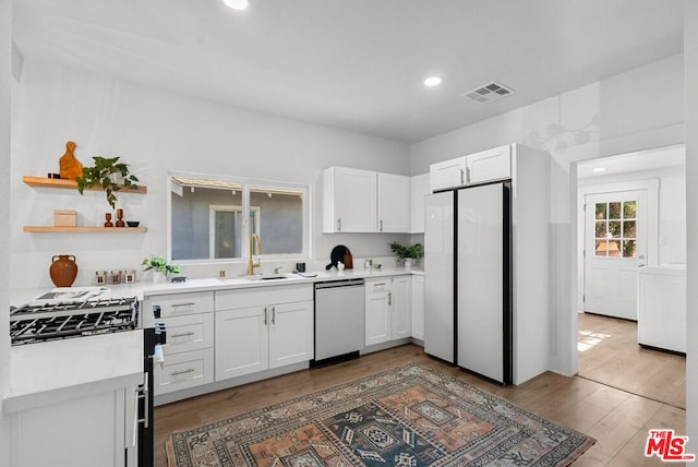 kitchen with dark wood-type flooring, white cabinets, white refrigerator, sink, and dishwashing machine