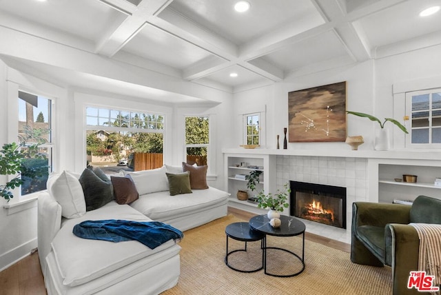 living room with hardwood / wood-style floors, coffered ceiling, beamed ceiling, and a tiled fireplace