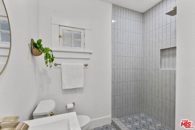 bathroom featuring tiled shower and toilet