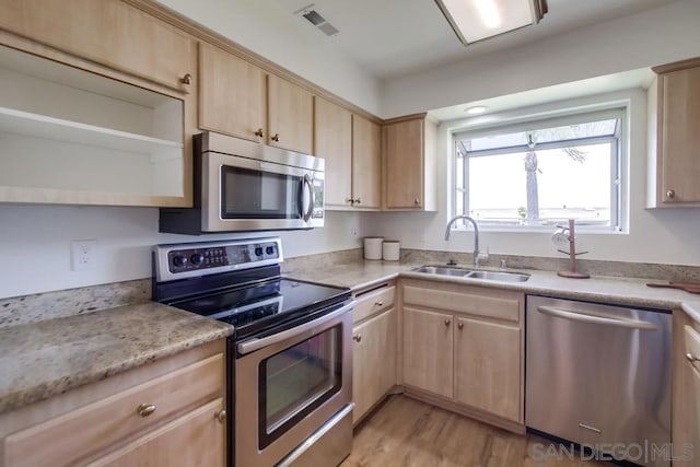 kitchen with light brown cabinetry, sink, light hardwood / wood-style flooring, and appliances with stainless steel finishes