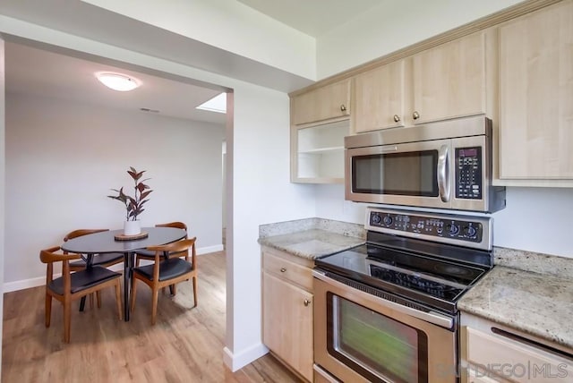 kitchen featuring light stone counters, light brown cabinetry, stainless steel appliances, and light hardwood / wood-style floors