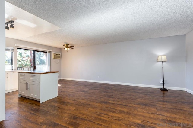 interior space with a textured ceiling, dark hardwood / wood-style floors, an AC wall unit, and ceiling fan