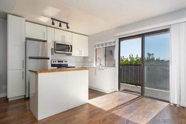 kitchen with wood counters, dark hardwood / wood-style flooring, a textured ceiling, stainless steel appliances, and white cabinetry