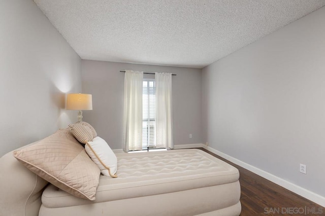 bedroom with a textured ceiling and dark wood-type flooring