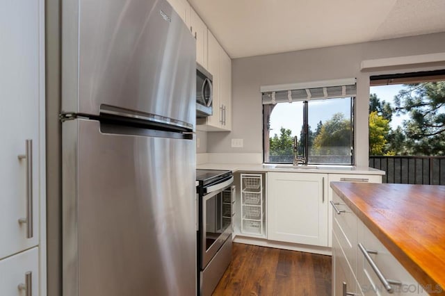 kitchen with sink, dark hardwood / wood-style floors, butcher block countertops, white cabinetry, and stainless steel appliances