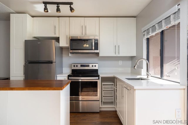 kitchen featuring dark wood-type flooring, sink, butcher block countertops, white cabinetry, and stainless steel appliances