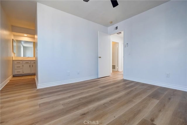 unfurnished bedroom featuring ensuite bath, light wood-type flooring, and ceiling fan