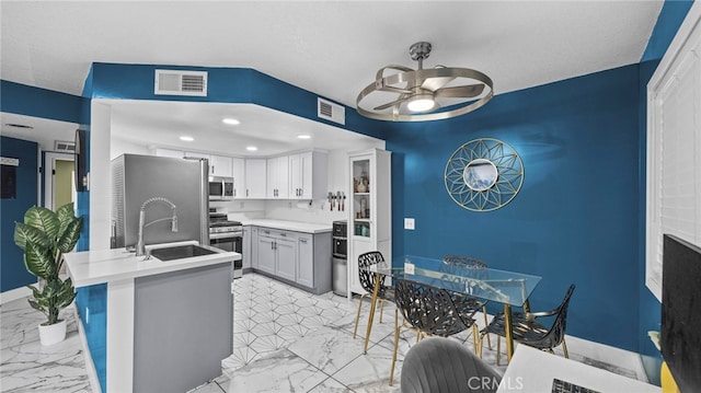 kitchen featuring kitchen peninsula, appliances with stainless steel finishes, ceiling fan, sink, and white cabinetry