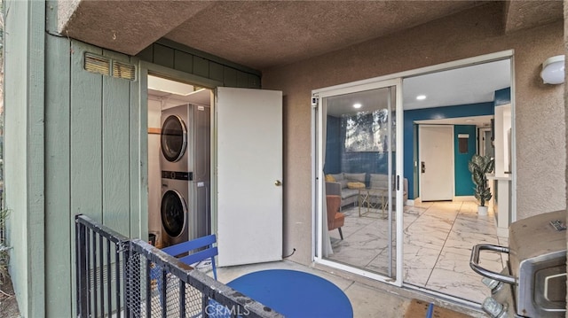 doorway to property with a balcony and stacked washer / dryer