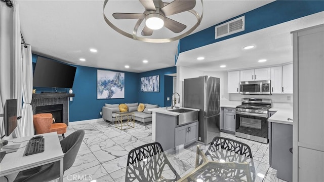 kitchen featuring gray cabinetry, ceiling fan, white cabinetry, and stainless steel appliances