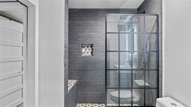 bathroom with toilet and a tile shower