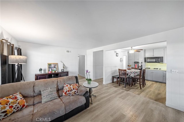 living room with light hardwood / wood-style floors and ceiling fan