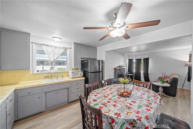 dining space featuring ceiling fan, sink, and light wood-type flooring