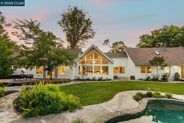 back house at dusk with a lawn