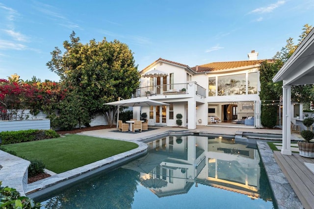 back of property featuring a lawn, a balcony, and a patio