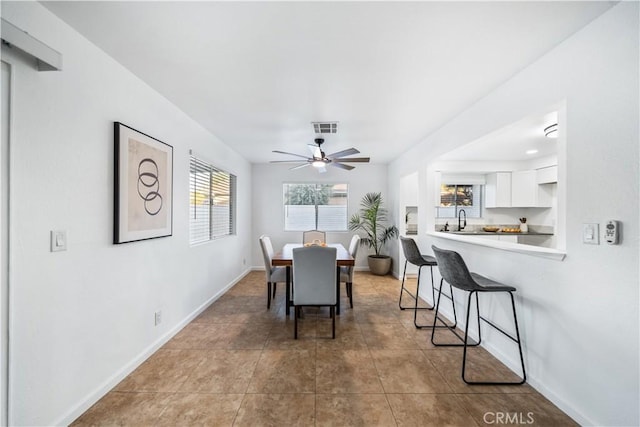 tiled dining room featuring ceiling fan and sink