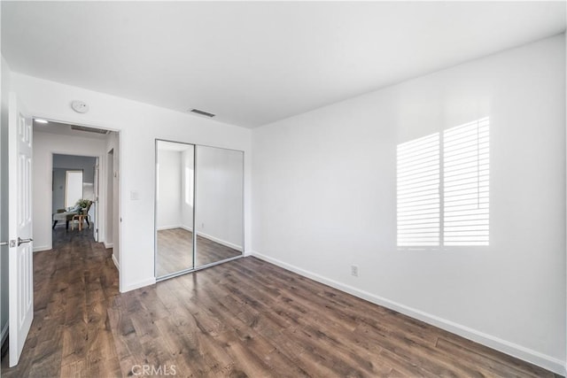 unfurnished bedroom with a closet and dark wood-type flooring