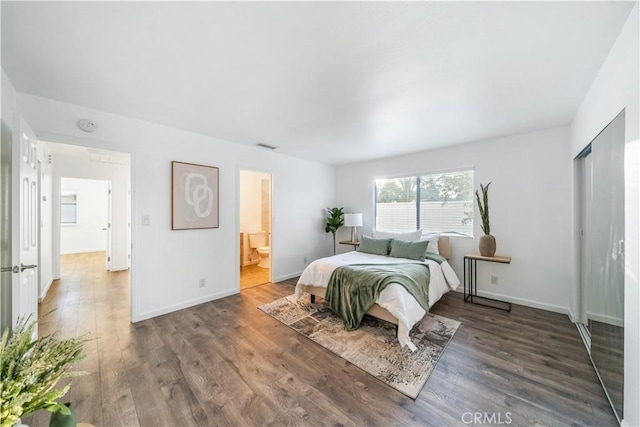 bedroom featuring ensuite bathroom and dark hardwood / wood-style floors