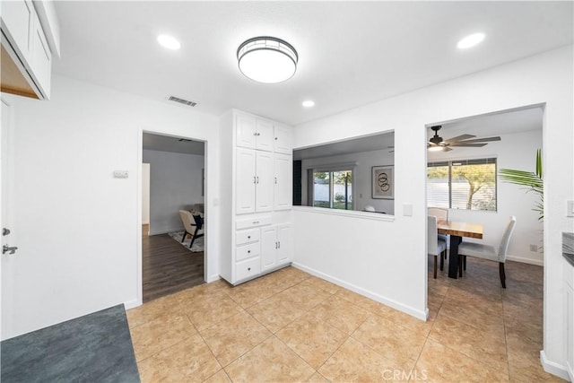 interior space featuring ceiling fan, white cabinets, and light tile patterned floors