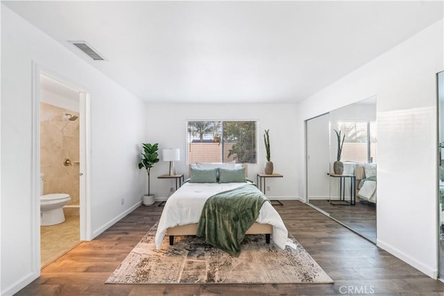 bedroom featuring ensuite bathroom, dark wood-type flooring, and a closet