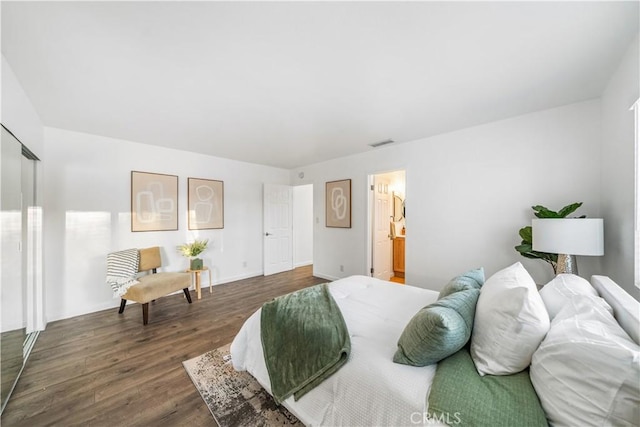 bedroom with connected bathroom and dark hardwood / wood-style floors