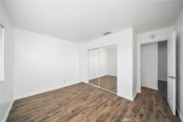 unfurnished bedroom featuring a closet and dark hardwood / wood-style flooring