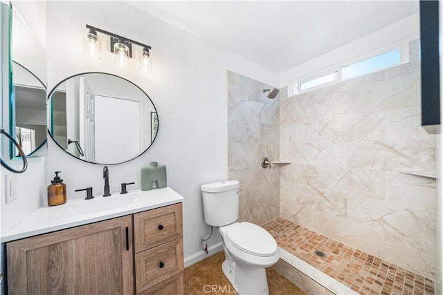 bathroom featuring tile patterned flooring, a tile shower, vanity, and toilet