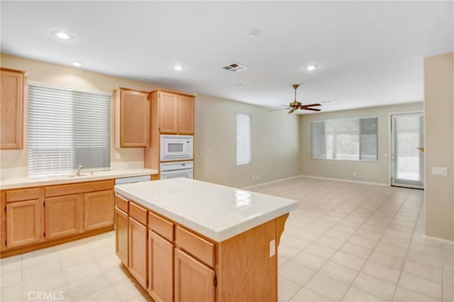 kitchen with ceiling fan, sink, tile countertops, white appliances, and a kitchen island