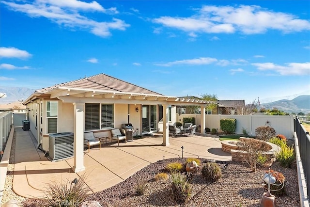 rear view of house featuring central AC unit, a patio area, a mountain view, and a fire pit