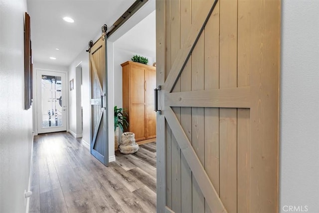 corridor with light hardwood / wood-style flooring and a barn door