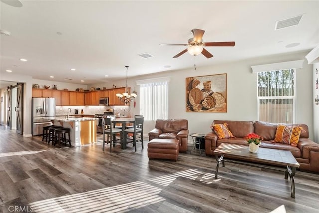 living room featuring dark hardwood / wood-style flooring, ceiling fan with notable chandelier, and sink