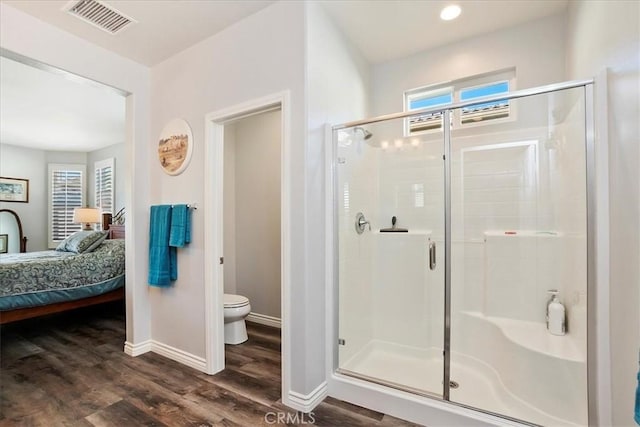 bathroom featuring a shower with shower door, wood-type flooring, and toilet