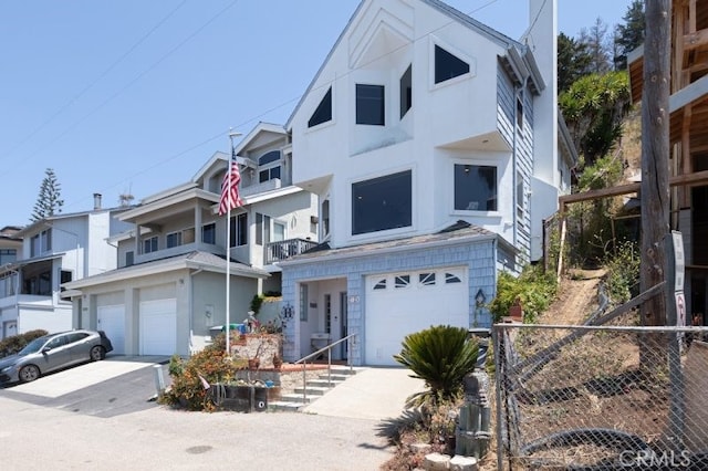 view of front of house featuring driveway, a garage, fence, and stucco siding