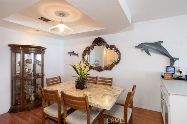 dining room with wood-type flooring and a tray ceiling