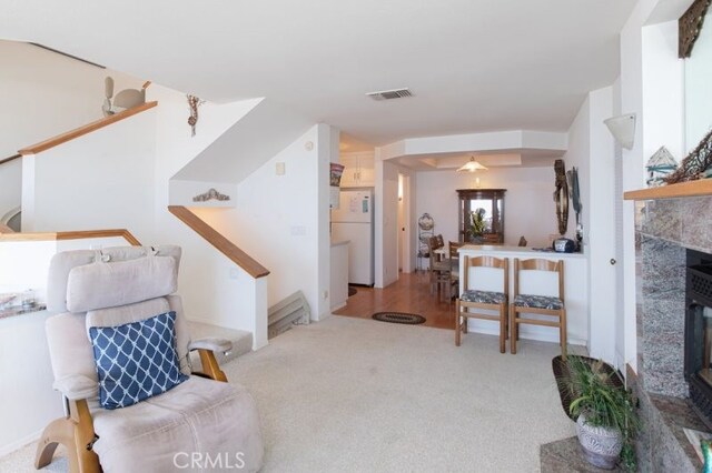 living room with a tile fireplace, light carpet, and ceiling fan