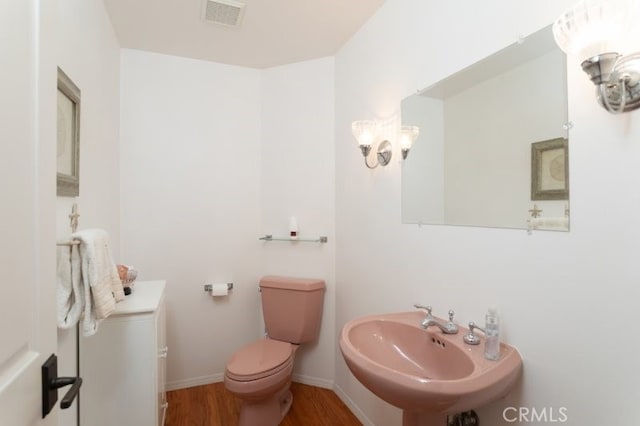 bathroom with a chandelier, wood-type flooring, toilet, and sink